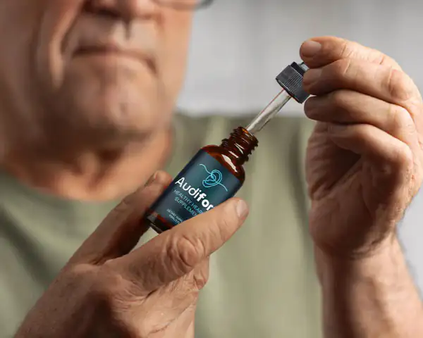 Audifort liquid hearing supplement dropper held in a hand, photo from the Active Health Guide Audifort review